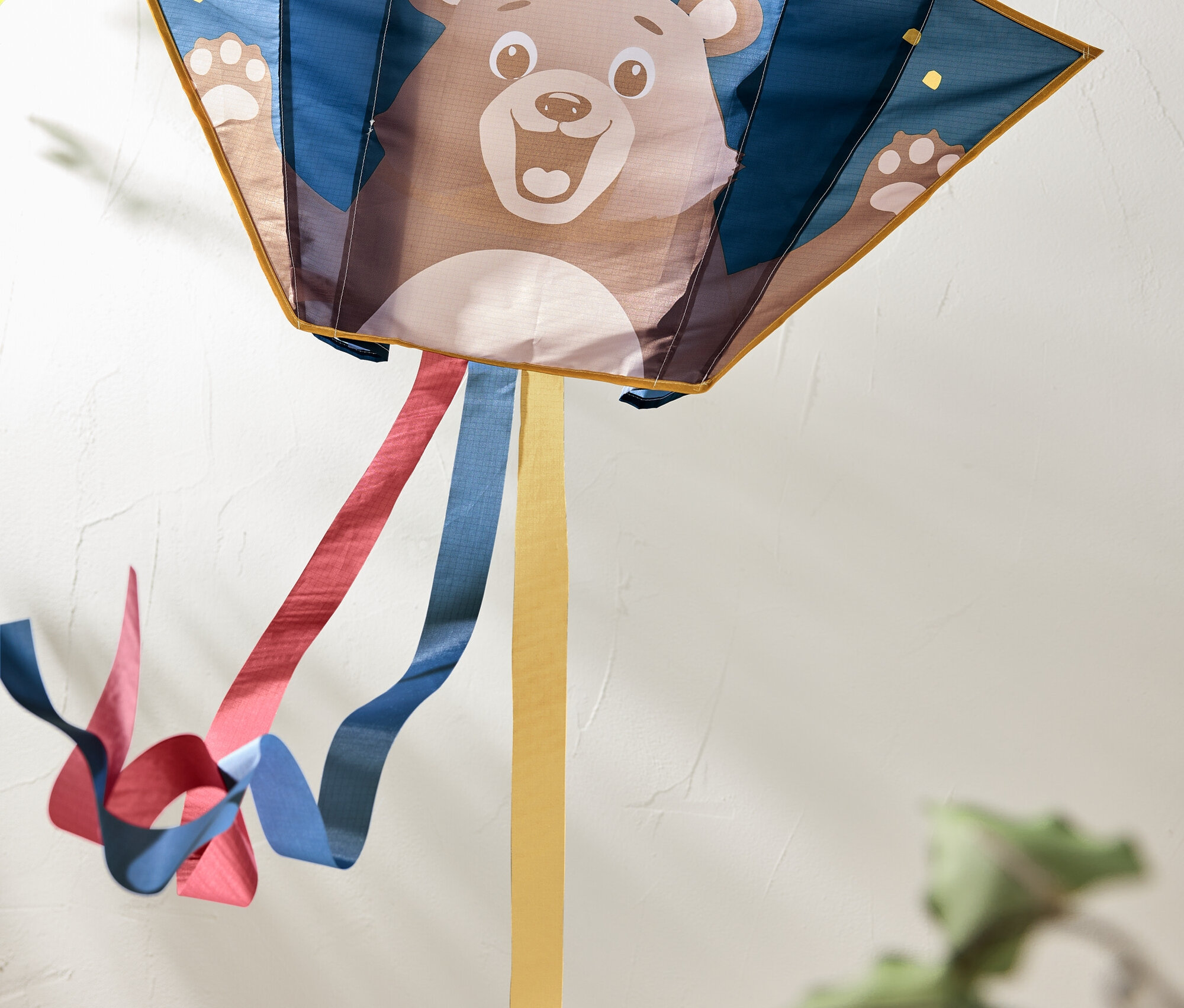 Ayı resimli ve arkasında renkli kurdeleler dalgalanan uçurtma.