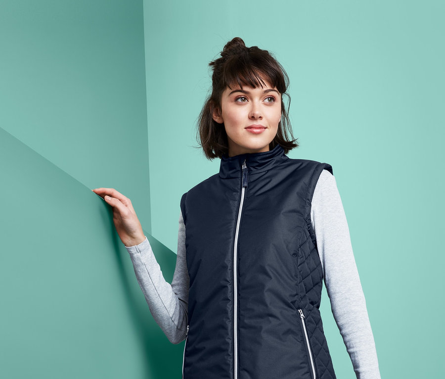 Kadın, geri dönüştürülmüş malzemeden lacivert bir binici yeleği giyiyor.