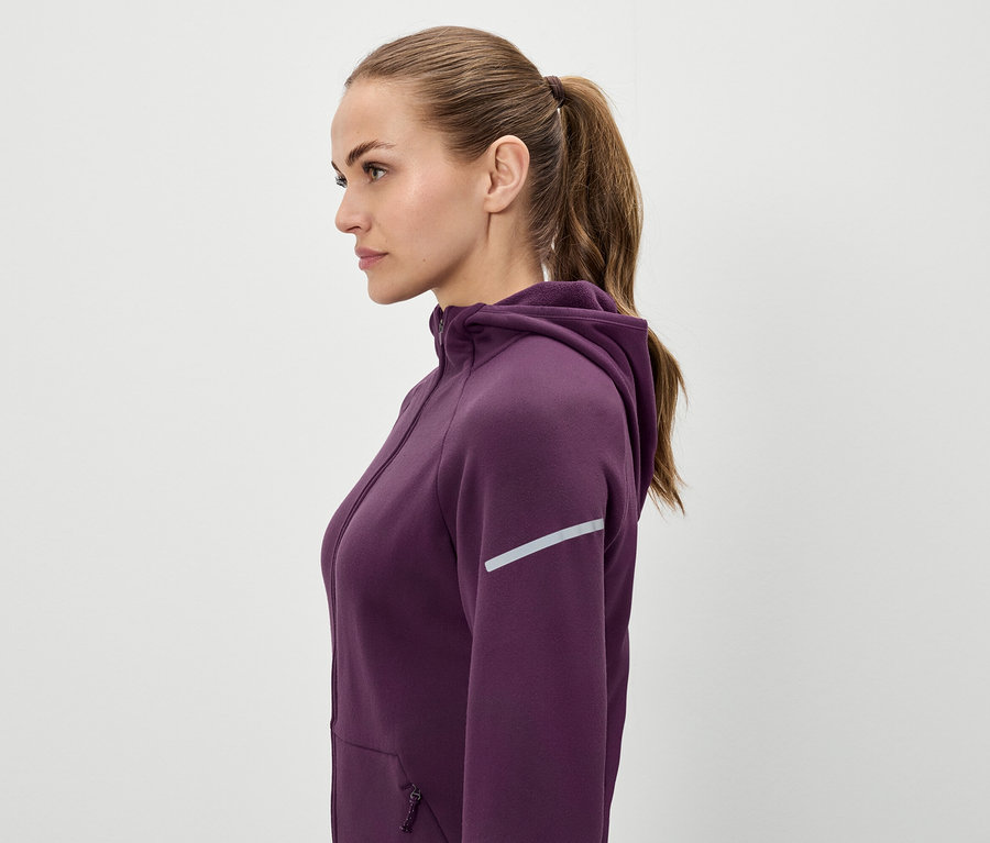 Kahverengi saçları at kuyruğu yapılmış, mor kapüşonlu bir sweatshirt giyen bir kadının profili.