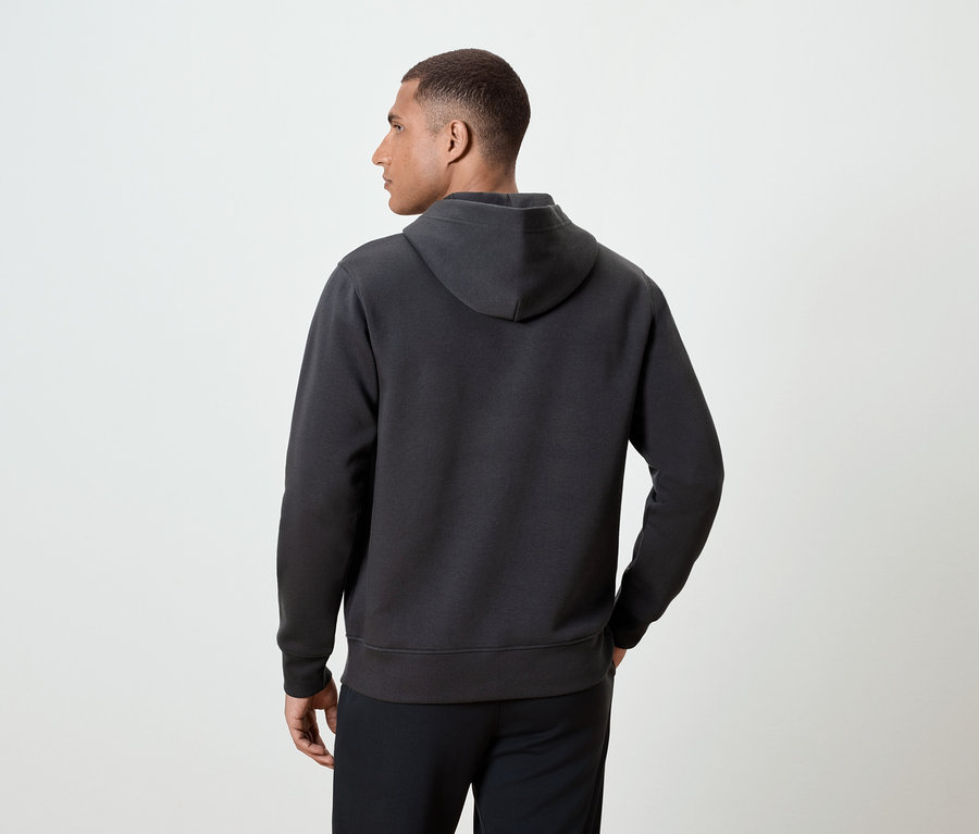 Arkası dönük bir adam koyu gri kapüşonlu bir sweatshirt giyiyor.