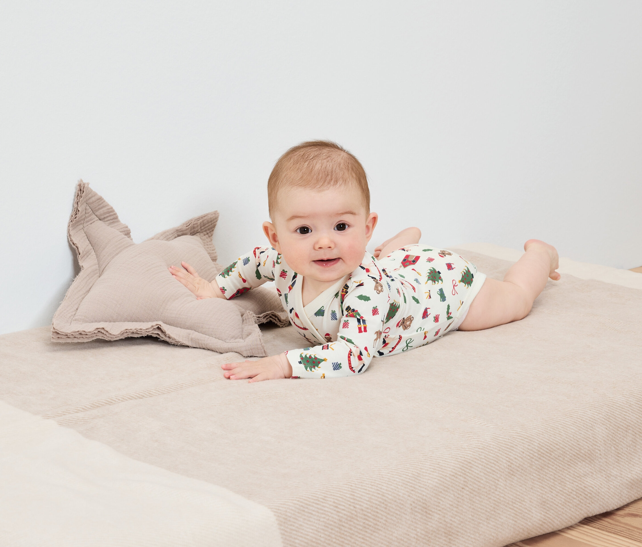 Bebek, yıldız şeklinde bir yastığın yanında bir battaniyenin üzerinde yüzüstü yatıyor.