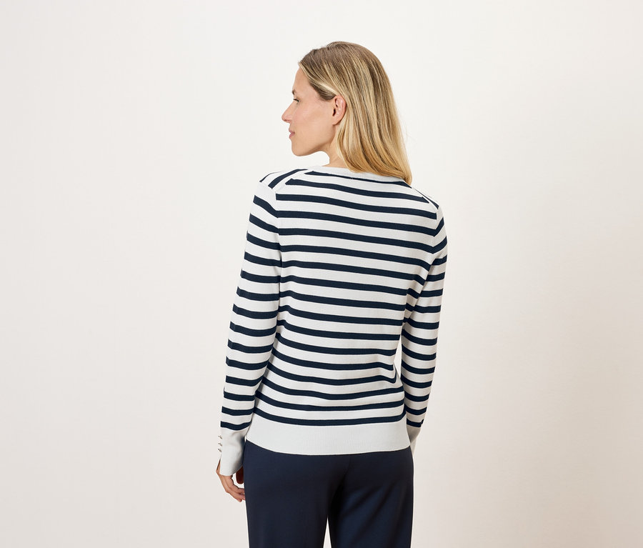 Arkadan uzun kollu çizgili bir kazak giyen sarışın bir kadın.