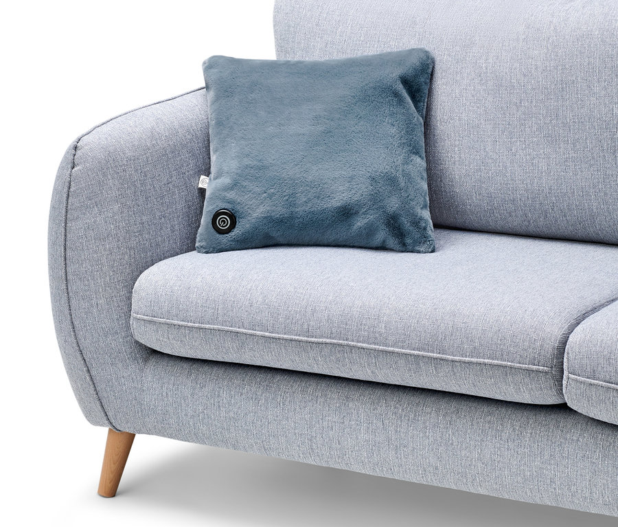 Mavi şarjlı ısıtma yastığı gri bir kanepenin üzerinde duruyor.