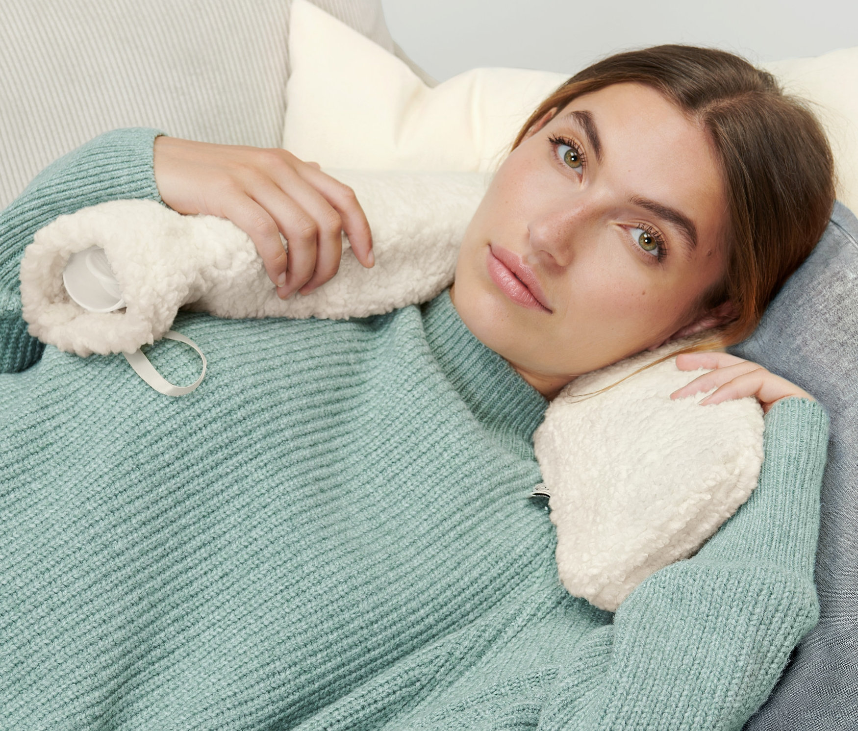 Kadın koltukta uzanmış, Uzun Sıcak Su Torbası tutuyor.