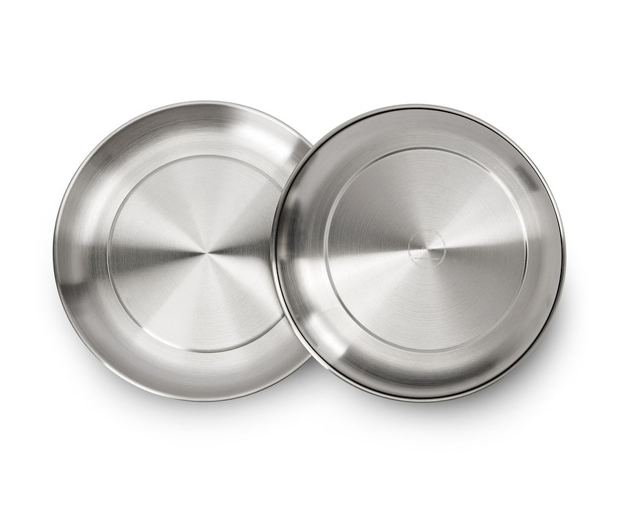 Beyaz bir arka plan üzerinde duran iki gümüş rengi kamp tabağı.