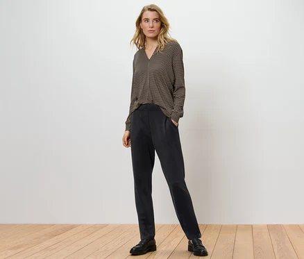 Kadın siyah joggpant ve desenli bir bluzla poz veriyor.