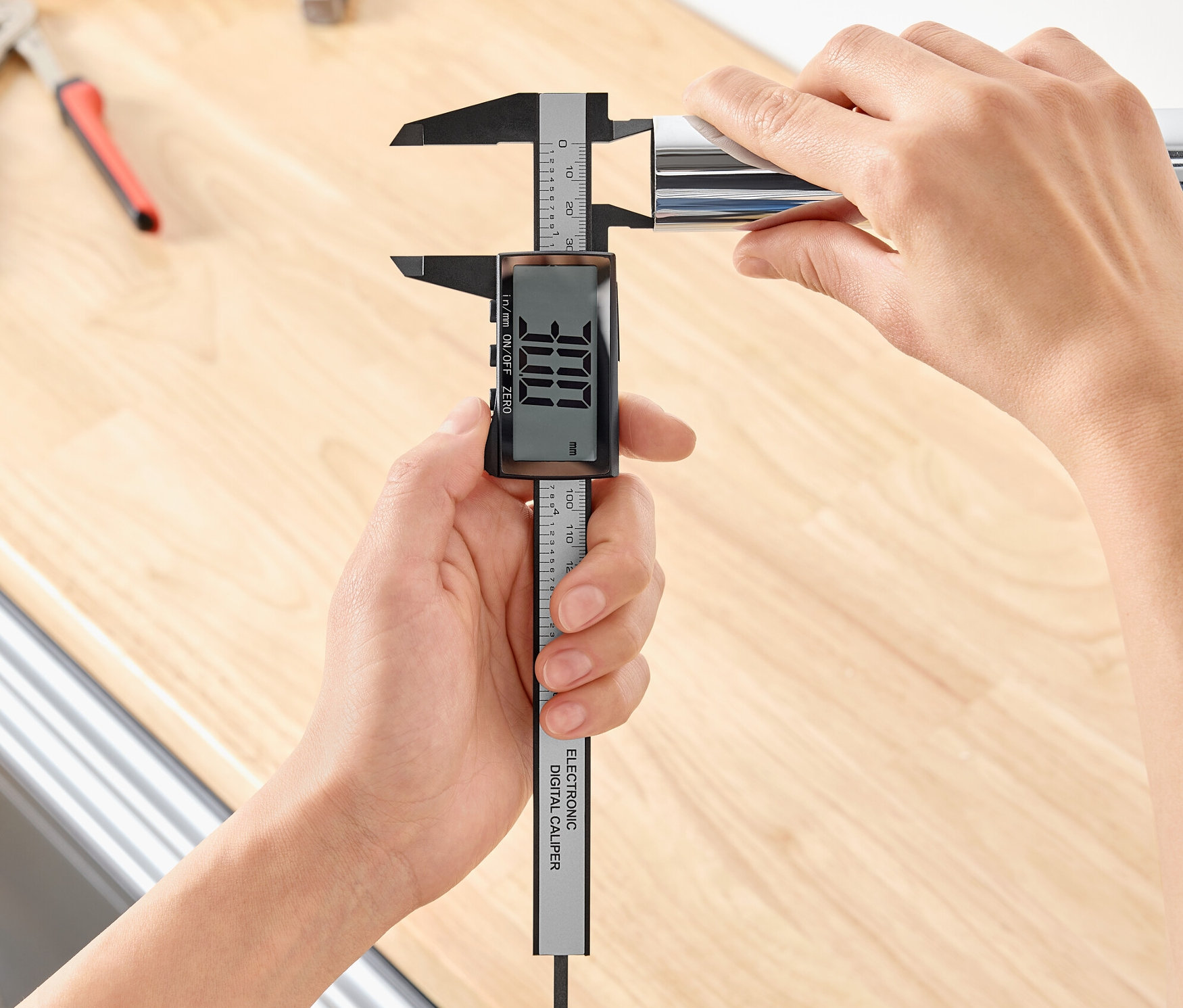 Bir kişi, dijital kumpas ile metal bir borunun çapını ölçüyor.