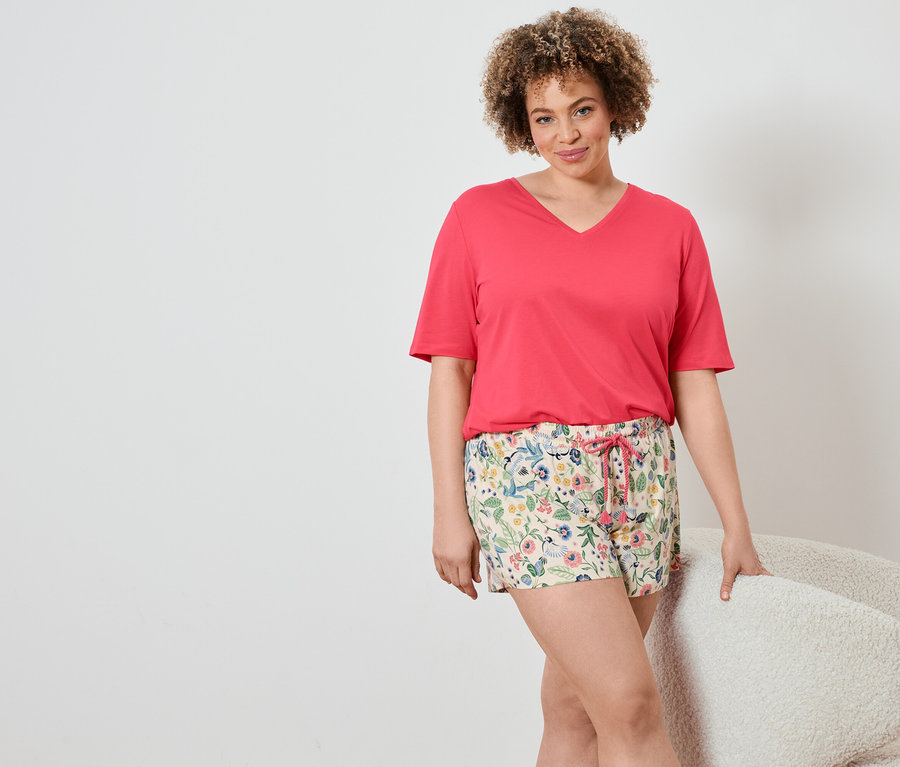 Kadın şortlu pijama takımı giyiyor.