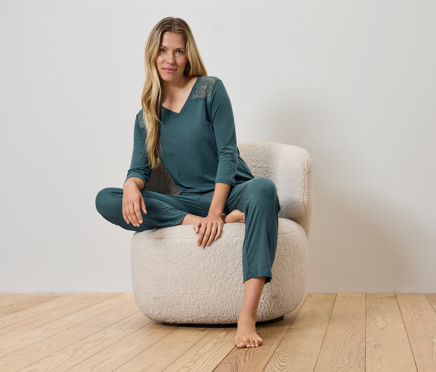 Kadın yeşil pijamasıyla tüylü bir sandalyede oturuyor.