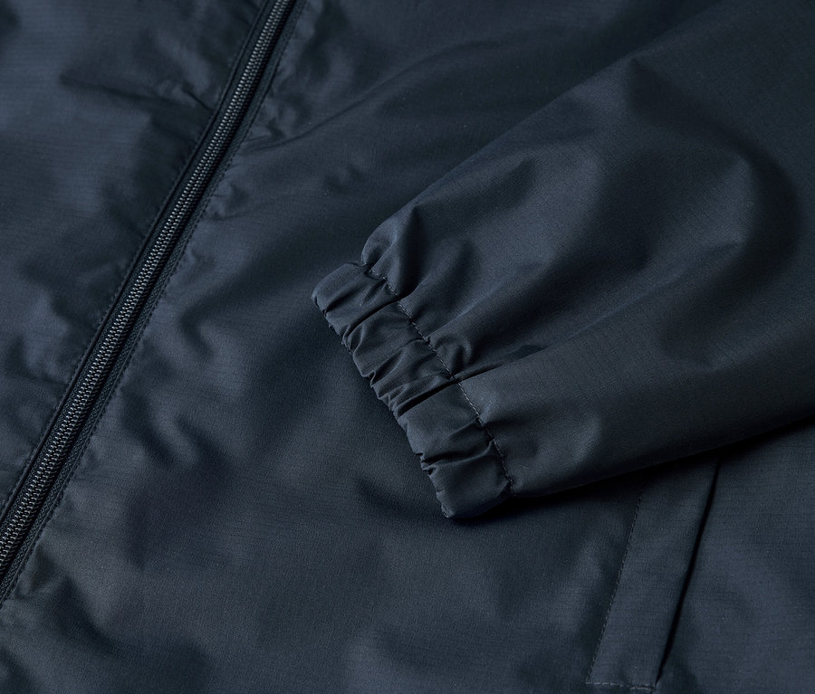Lacivert bir ceket, fermuar ve elastik manşetlerin yakın çekimi.