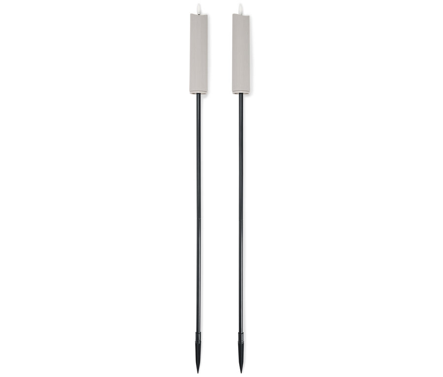 Beyaz bir arka plan üzerinde yan yana duran, siyah saplı iki bej bahçe meşalesi.