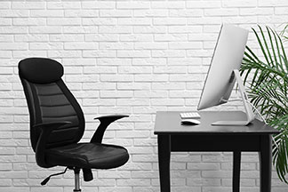 Üzerinde bir bilgisayarın durduğu siyah ofis masasının önündeki siyah ofis sandalyesi.