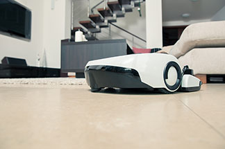 Elektrikli yardımcı: Bir temizlik robotu, fayanslarla döşenmiş bir oturma odası zemini üzerinde hareket eder.