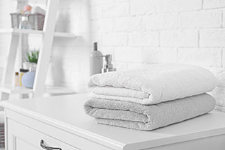 Rahat bir banyo için aksesuarlar: Banyodaki bir komodinin üzerinde katlanmış iki adet yumuşak havlu bulunuyor.